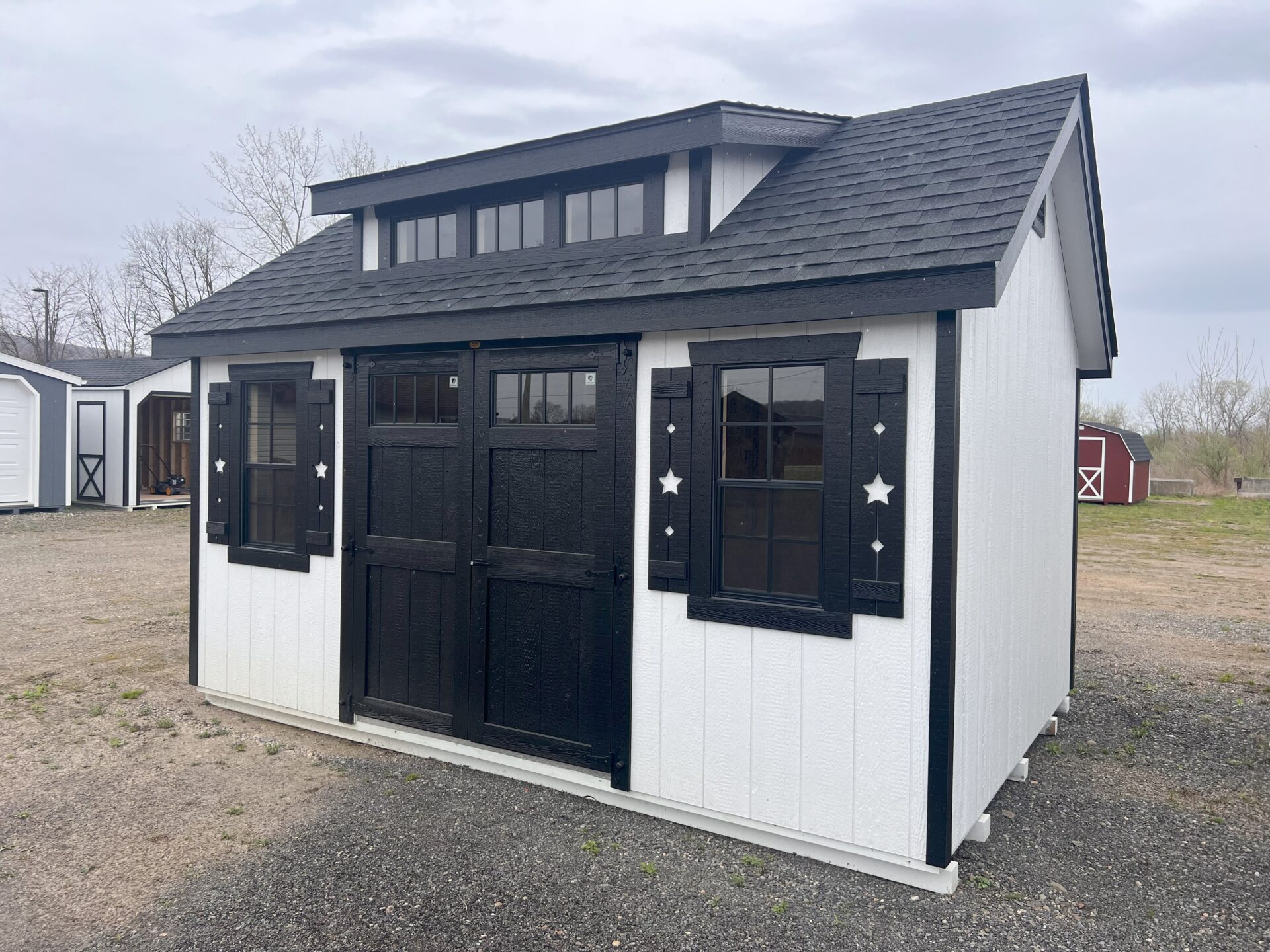 White shed with black double doors, windows and transom dormer