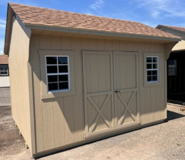 Tan shed with double doors, two windows and shingled roof