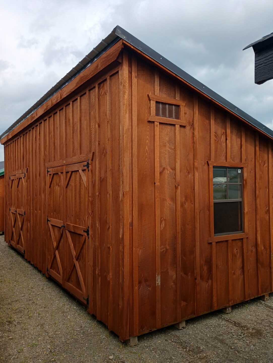Large one slanted building with board and batten siding, two double doors and windows on either end